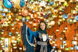 دانلود عکس با کیفیت دختر زیبا با لباس سنتی ترکیه در بازار چراغ و لوستر