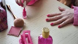 دانلود فوتیج زن در حال زدن لاک صورتی به انگشتان با وسایل صورتی روی میز