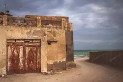 دانلود عکس خانه بسیار قدیمی در کنار دریا با درهای زنگ زده در جزیره قشم