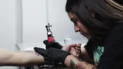 دانلود فوتیج یک زن تتوکار در حال تتو روی دست با تمرکز