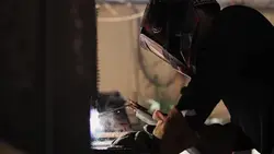 دانلود فوتیج جوشکار در حال جوشکاری یک قطعه فلزی در کارگاه