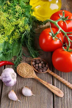 دانلود تصویر شاتراستوک یک بوته گوجه فرنگی و قاشق و سیر و فلفل و روغن روی میز چوبی کد۰۷۹۳۹۶۰۳۰۸