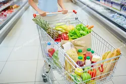 عکس با کیفیت تبلیغاتی سبد چرخدار فروشگاه در دست زن و سبد پر شده از سبزیجات و میوه و مواد غذایی