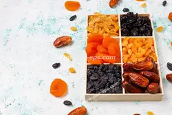 عکس با کیفیت تبلیغاتی کشمش و خرما خشک و آلو زرد خشک در داخل ظرف اردو خوری بر روی میز سفید