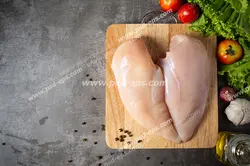 عکس با کیفیت تبلیغاتی سینه مرغ بر روی تخته تخته گوشت و سبزیجات در کنارش