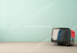 عکس با کیفیت تبلیغاتی تلویزیون قدیمی در گوشه ای از اتاق و کاغذ دیواری به رنگ آبی