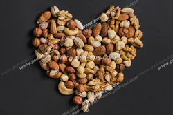 عکس با کیفیت تبلیغاتی آجیل و خشکبار به شکل قلب در بک گراند تیره