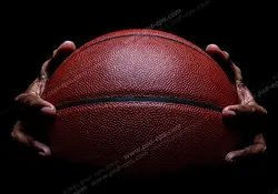عکس با کیفیت تبلیغاتی توپ بسکتبال بین دو دست در تاریکی