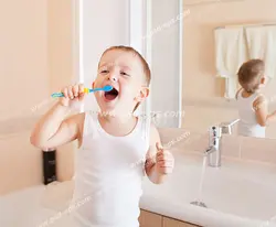 عکس با کیفیت تبلیغاتی کودک زیبا در حال مسواک زدن پشت به آینه