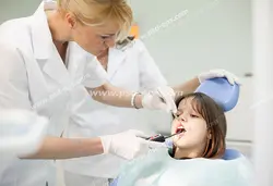 عکس با کیفیت تبلیغاتی خانم دندانپزشک در حال معاینه دندان های دختر بچه