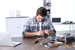 عکس با کیفیت تبلیغاتی مرد در حال تعمیر برد لپ تاپ روی میز با ابزار تعمیر و فن و پیچ گوشتی و لپ تاپ و کمد