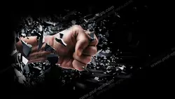 عکس با کیفیت تبلیغاتی دست مشت شده که به محکمی دیوار را شکافته و تکه های شکسته شده دیوار به اطراف پرتاب شده است