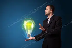 عکس با کیفیت تبلیغاتی مرد با لباس رسمی و کراوات که لامپ بزرگ با نور سبز را بین دست هایش نگه داشته است و به افق دور خیره شده است