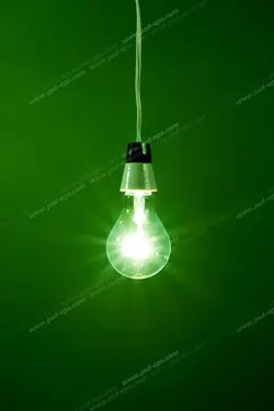 عکس با کیفیت لامپ رشته ای قدیمی روشن آویزان از سقف با زمینه سبز رنگ