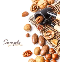 عکس با کیفیت دستگاه دستی گردو شکن به همراه آجیل های مختلف اعم از گردو ، فندق و بادام در کنار آن