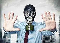 عکس با کیفیت مردی در شهری با هوای آلوده با ماسک شیمیایی در حال نشان دادن علامت Stop با دستانش