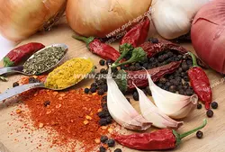 عکس با کیفیت پیازها و سیر و فلفل قرمز و انواع ادویه ها بر روی میز چوبی
