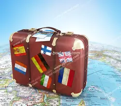 عکس با کیفیت چمدان قهوه ای قدیمی با تمبرهای مختلف بر روی کره بزرگ نقشه جهان
