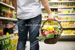 عکس با کیفیت مشتری فروشگاه زنجیره ای با سبد چوبی در دست در حال خرید میوه و سبزیجات