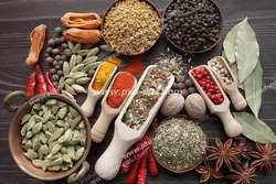 عکس با کیفیت انواع ادویه و محصولات اولیه تهیه ادویه درون ظروف و پیمانه ها بر روی میز