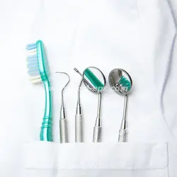 عکس با کیفیت ابزار و وسایل دندان پزشکی به اضافه مسواک قرار گرفته در جیب روپوش پزشکی