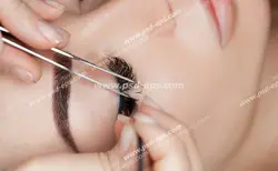 عکس با کیفیت چهره بانویی از نمای نزدیک در حال انجام کاشت و یا اکستنشن مژه