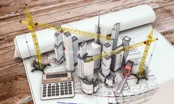 عکس با کیفیت نقشه های طراحی ساختمان باز شده روی میز همراه با ماکت برج ها و تاور کرین