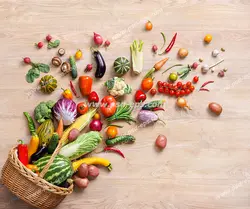 عکس با کیفیت قارچ و سبزیجات و میوه های مختلف در سبد چوبی با چیدمانی زیبا بر روی میز چوبی