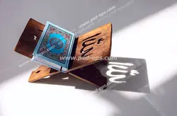عکس با کیفیت نمایی از کنار و تابش آفتاب بر روی قرآن و رحل با نقش کلمه الله