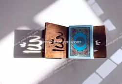 عکس با کیفیت نمایی از بالا و تابش آفتاب بر روی قرآن درون رحل با نقش کلمه الله بر روی رحل