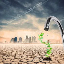 عکس با کیفیت چکیدن قطره آبی در بیابان بر روی گیاه کوچک با زمینه شهر مدرنی در بیابان