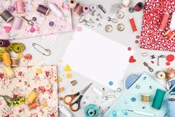 عکس با کیفیت انواع پارچه طرح دار و گل دار در کنار ابزار خیاطی و نخ های رنگارنگ