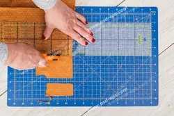 عکس با کیفیت خیاط در حال کشیدن الگو بر روی پارچه با رولت خیاطی بر روی برگه دقیق اندازه گیری