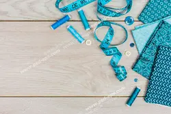 عکس با کیفیت پارچه ، متر ، نخ ها و دکمه های آبی و ابزار خیاطی روی میز چوبی