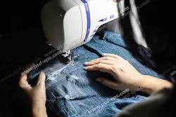 عکس با کیفیت دوخت پارچه لی زخمی برای شلوار لی آبی رنگ با چرخ خیاطی توسط خیاط ویژه استفاده در امور تبلیغاتی و تجاری طراحی کاتالوگ ، بروشور و تراکت با موضوع خیاطی ، تولیدی لباس ، آموزش خیاطی یا موسسات فنی و حرفه ای آموزش مقدماتی تا حرفه ای