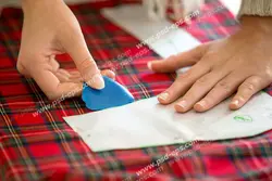 عکس با کیفیت انداختن الگو بر روی پارچه چهارخانه قرمز و آبی و کشیدن طرح الگو با صابون خیاطی ویژه استفاده در امور تبلیغاتی و تجاری طراحی کاتالوگ ، بروشور و تراکت با موضوع خیاطی ، تولیدی لباس ، آموزش خیاطی یا موسسات فنی و حرفه ای آموزش مقدماتی تا حرفه ای و لباس شب و لباس عروس