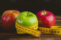 عکس با کیفیت سیب های سبز و قرمز و متر با مفهوم رژیم لاغری و رژیم با میوه های ترش یا دانلود عکس سه سیب با متر خیاطی به دور آن ویژه رژیم غرایی سالم خواری