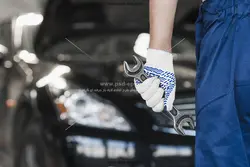 عکس با کیفیت تعمیرکار با آچار در دست با قصد تعمیر ماشین با زمینه خودرو یا دانلود عکس با کیفیت تعمیر کار خودرو با آچار در دست و خودرو به رنگ مشکی