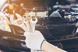عکس با کیفیت ابزارآلات تعمیرات در دستان تعمیرکار ماشین با زمینه خودرو یا عکس انواع آچار در دستی با دست کش پوشیده و کاپوت باز اتومبیل