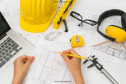 عکس با کیفیت طراحی ساختمانی و نقشه کشی با کلاه زرد ایمنی و ابزار نقاشی روی طرح و شخصی در حال نقشه کشی