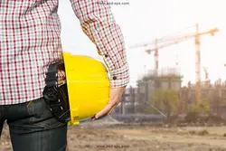 عکس با کیفیت مهندس با کلاه ایمنی زرد با پس زمینه ساختمان های در حال ساخت مناسب برای شرکت های ساختمانی و مهندسان عمران
