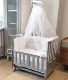 گهواره چوبی و تخت کنار مادر