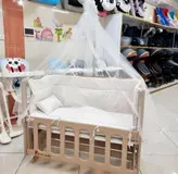 گهواره چوبی و تخت کنار مادر
