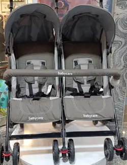 کالسکه دوقلو عصایی بغل هم رنگ طوسی خاکی بیبی کر با گارد محافظ جلو کالسکه  Baby Care Double Stroller