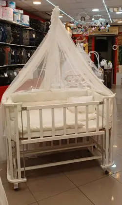 تخت کنار مادر گهواره شونده  تمام چوب  سایز 110 در 60 سانت دارای تنظیم ارتفاع و دارای درب باز شو اسانسوری رنگ کرم روشن بسیار زیبا و سرویس خواب و تشک و توری پشه بند  bebetto