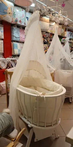 تخت و گهواره نوزادی تمام چوب بیضی رنگ کرم روشن با سرویس خواب و توری پشه بند  chipolino