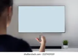 A woman with remote control sitting on couch and watching TV at home (Smart TV), space for design on screen. Business, logo, free space to use. Artificial grass and soundbar in the background. | یک زن با کنترل از راه دور روی نیمکت و تماشای تلویزیون در خانه (تلویزیون هوشمند) ، فضای طراحی روی صفحه نمایش.تجارت ، آرم ، فضای آزاد برای استفاده.چمن مصنوعی و نوار صدا در پس زمینه. – آکادمی پرنیان طرح