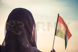 عکس استوک زن مسلمان روسری با پرچم ایران در غروب آفتاب