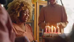 فوتیج زن سیاه پوست در حال دمیدن شمع روی کیک تولد