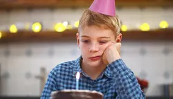 فوتیج کودکی تنها که در کنار کیک تولد نشسته